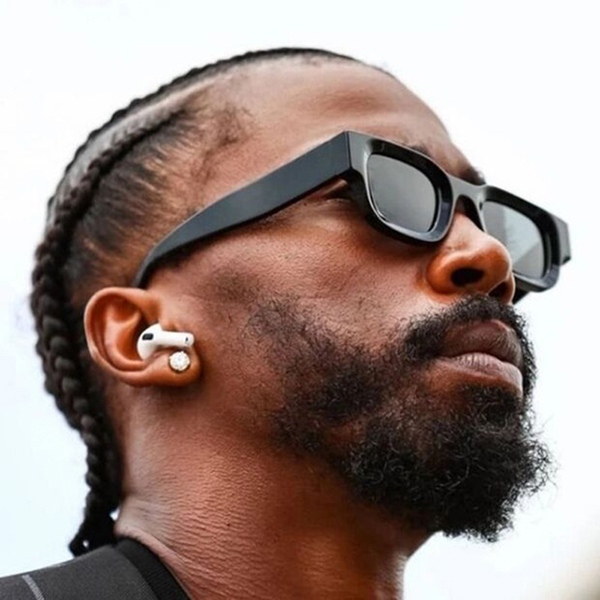 A celebrity posing at an event with subtly branded sunglasses