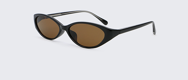 A person wearing dark sunglasses sitting alone in a cafe, looking thoughtful.