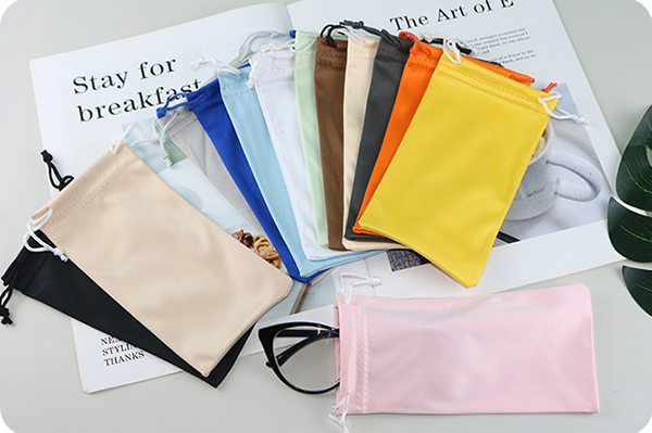 A person cleaning sunglasses lenses with a microfiber cloth while traveling