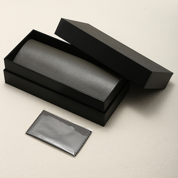 A sunglasses case being packed in the center of a suitcase surrounded by clothes